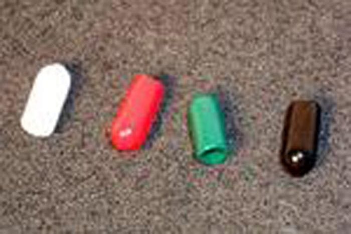 Four capsules in a row on a textured surface: white, red, green, and black.