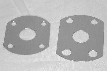 Two metal gaskets with four bolt holes and a central opening are placed side by side on a white surface.