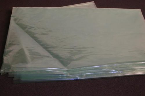 A stack of translucent green plastic sheets lies on a dark surface.