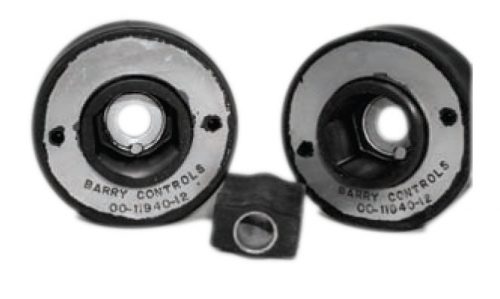 Two round mechanical parts with central holes, marked "Barry Controls," are positioned side by side. A smaller rectangular piece with a hole is placed in front of them. The parts appear to be components for vibration control.