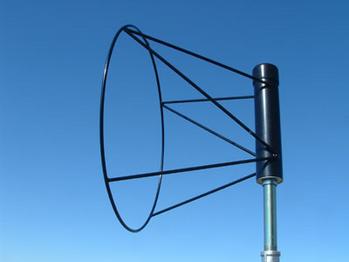 A black helical antenna with a conical shape mounted on a pole against a clear blue sky.