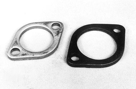 Two metal gaskets with circular centers and two bolt holes each, one silver and one black, placed on a white surface.