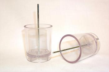Two transparent plastic cups, one standing upright with a metal rod inside and the other lying on its side, against a plain background.