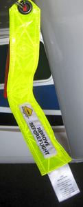 A bright yellow "Remove Before Flight" tag is attached to an aircraft part. The tag is long and rectangular with a black and red attachment at the top.