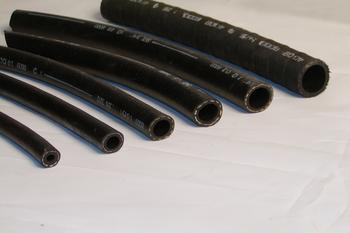 Seven black rubber hoses of varying diameters are arranged on a white surface, showcasing their open ends.