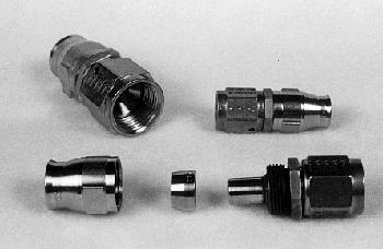 Five metal coaxial cable connectors are arranged on a flat surface. They vary in size and shape, with some appearing disassembled, showing internal threading and components.