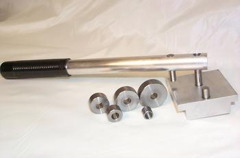 Metal tool with a long handle, three cylindrical components, and a rectangular base with two protruding rods, placed on a white surface.