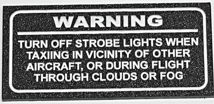 Warning sign instructing to turn off strobe lights when taxiing near other aircraft or flying through clouds or fog.