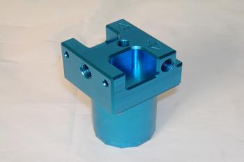 Blue metal bracket with a square opening on top and a cylindrical base, featuring multiple holes on its sides, placed on a light surface.